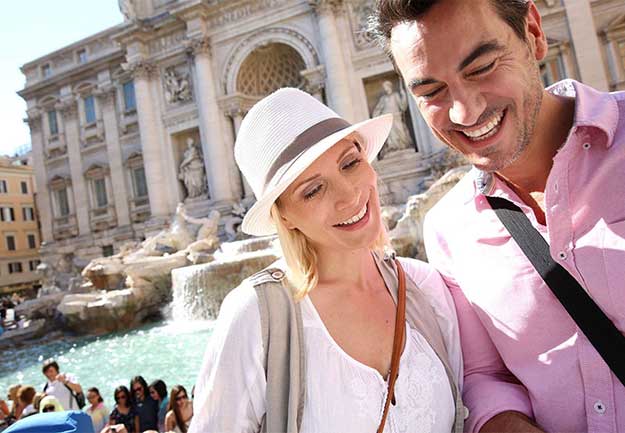 a man and woman smiling in front of a fountain