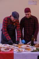 two men cutting food in a room